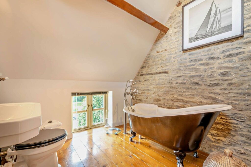 Beautiful bathroom with Cotswold stone wall and stand alone bath